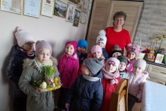 Dzieci ustawione w grupce, za nimi stoi Pani sołtys, jedna dziewczynka z przodu trzyma w rękach stroik.