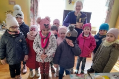 Dzieci stoją ustawione w dwóch rzędach, za nimi pani Stasia, która trzyma w rękach koszyczek wielkanocny od dzieci.
