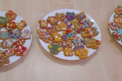 Na stole leży trzy talerze z udekorowanymi pierniczkami.