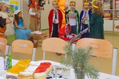  Trzech chłopców przebranych za królów, na stołku siedzi Maryja, przed nią żłóbek z Jezuskiem.