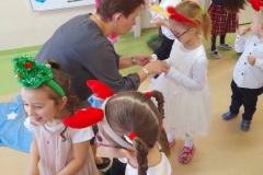 Wychowawczyni łamie się opłatkiem z dziewczynka, w tle inne dzieci.