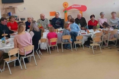 Przy stolikach ustawionych w podkowe siedzą zaproszeni goście, dzieci po przeciwnej stronie.