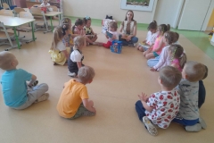 Kilkoro dzieci siedzi wokół pani z biblioteki, dopasowują minki do zachowań misia.