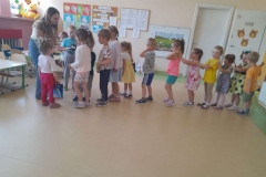 Dzieci stoją w pociągu, pani rozdaje im nagrody zakładki do książki.