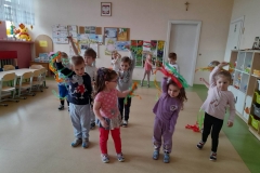 Dzieci stoją w rozsypce, poruszają kolorowymi paskami bibuły w rytm muzyki