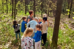 Grupa dzieci wsłuchuje się w głosy lasu.