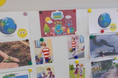 Na tablicy w sali przedszkolnej przypięte są magnesami obrazki tematyczne z niebiesko - zielonym hasłem: Dzień Ziemi. Po lewej stronie widok planety Ziemi z uśmiechniętą żółtą emotką oraz obrazki z sadzeniem roślin i segregowaniem śmieci. Po prawej stronie widok Ziemi ze smutną emotką i obrazki dymu z komina, wysypanych przy drodze śmieci oraz dzieci zaśmiecających otoczenie.