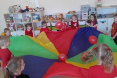 Dzieci trzymają kolorową chustę Klanzy, liczą ile balonów na niej zostało