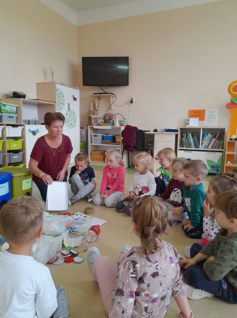 Dzieci siedzą w kole na podłodze przed nimi kolorowe kosze utrwalają kolory